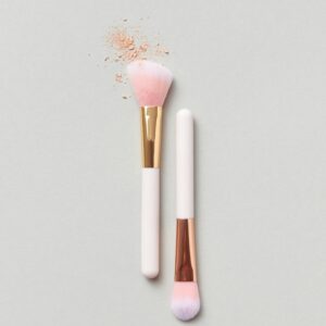 Elegant makeup brushes with blush powder in a minimalist flat lay design.
