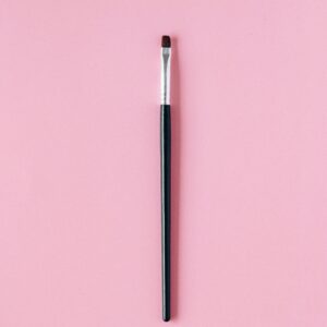 High-quality image of a makeup brush on a pastel pink background for beauty themes.